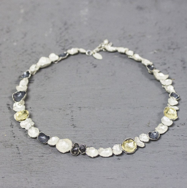 Collier gemaakt van 925 sterling zilver, geoxideerd zilver en zilver verguld. Dit schakelcollier is door de drie kleuren en verschillende organische schaaltjes een echt J&eacute;h collier.